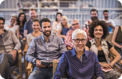 Crowd of business people attending a business seminar in a board room. Focus is on mature woman looking at camera.