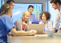 a mixed group of healthcare professionals and business people meet around a conference table