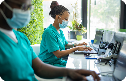 Nurse with protective face mask working on laptop on reception of medical clinic