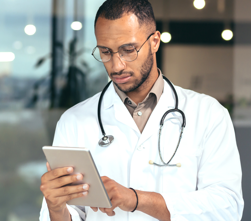 Serious and focused thinking african american doctor using tablet computer, man working inside modern clinic office