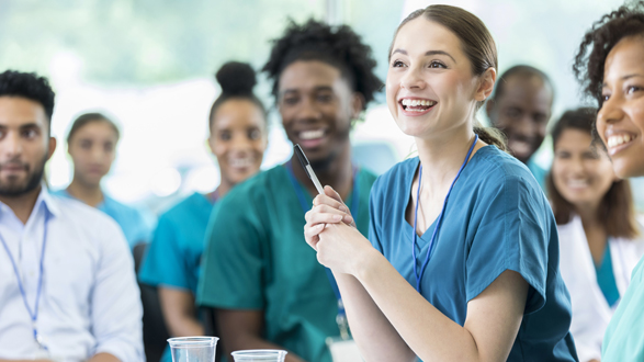 Cheerful Hispanic female nursing students smiles as she listens to a professor's lecture.