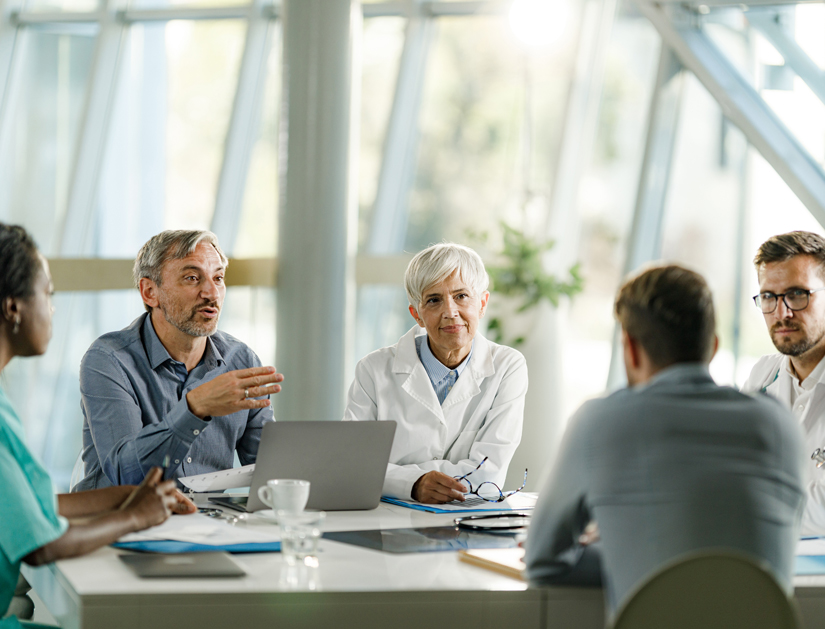 Team of doctors and businessmen communicating while having a meeting at doctor's office in the hospital.