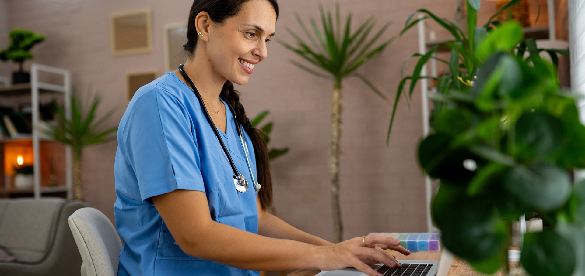 Female medical intern in blue medical scrubs e-learning on laptop at the ordination