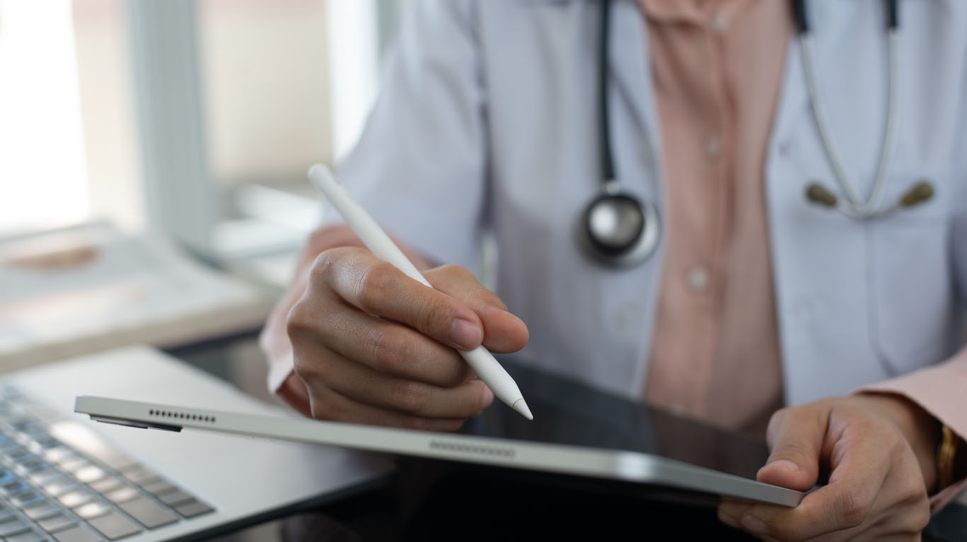 Female doctor working, using digital tablet at doctor's office. writing prescription, recording patient's information, healthcare and medicine concept
